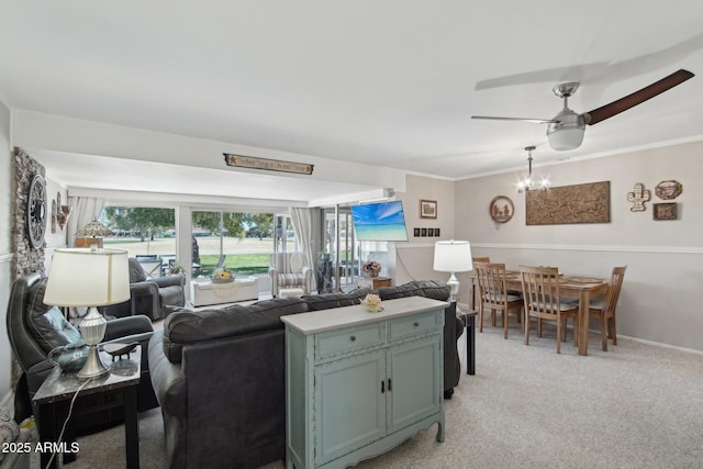 living room featuring light carpet, baseboards, crown molding, and ceiling fan with notable chandelier