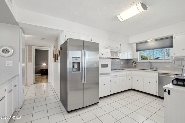 kitchen with white cabinetry, stainless steel appliances, a sink, and light countertops