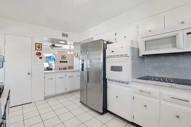 kitchen with light countertops, visible vents, backsplash, white cabinets, and white appliances