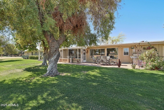 back of property featuring a yard, a patio area, and a sunroom