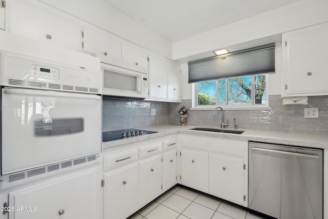 kitchen with white appliances, a sink, white cabinets, and decorative backsplash