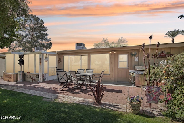 back of property at dusk featuring a patio