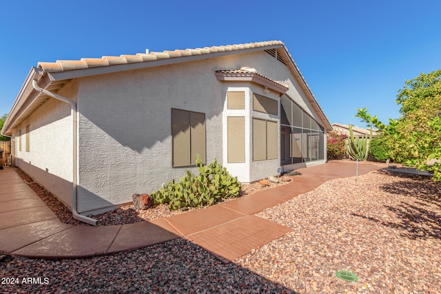 view of property exterior featuring a patio area and a sunroom