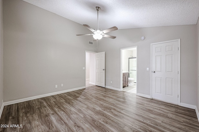 empty room with a textured ceiling, hardwood / wood-style flooring, high vaulted ceiling, and ceiling fan