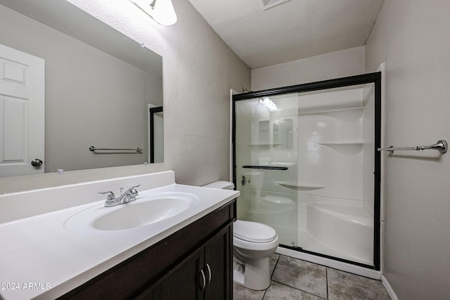 bathroom featuring vanity, toilet, a shower with shower door, and tile patterned floors