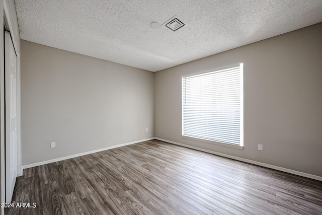 empty room with hardwood / wood-style floors and a textured ceiling