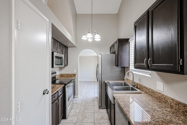 kitchen featuring light tile patterned flooring, appliances with stainless steel finishes, a notable chandelier, and stone counters