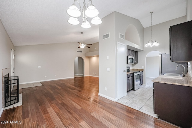 living room with ceiling fan with notable chandelier, high vaulted ceiling, sink, and light hardwood / wood-style floors