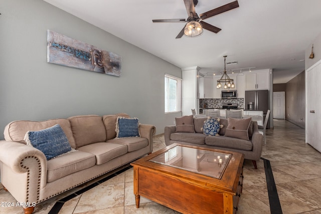 living room with light tile patterned flooring and ceiling fan with notable chandelier