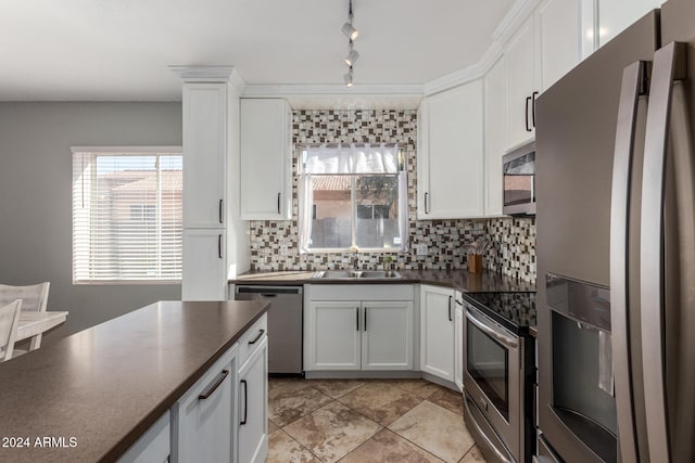 kitchen featuring decorative backsplash, track lighting, white cabinetry, sink, and stainless steel appliances