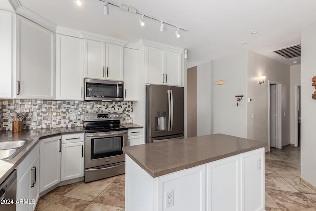 kitchen featuring appliances with stainless steel finishes, white cabinets, tasteful backsplash, and a center island