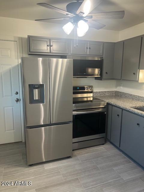 kitchen with stainless steel appliances, ceiling fan, and gray cabinetry