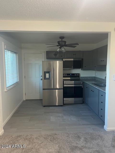 kitchen featuring ceiling fan, stainless steel appliances, a textured ceiling, and sink