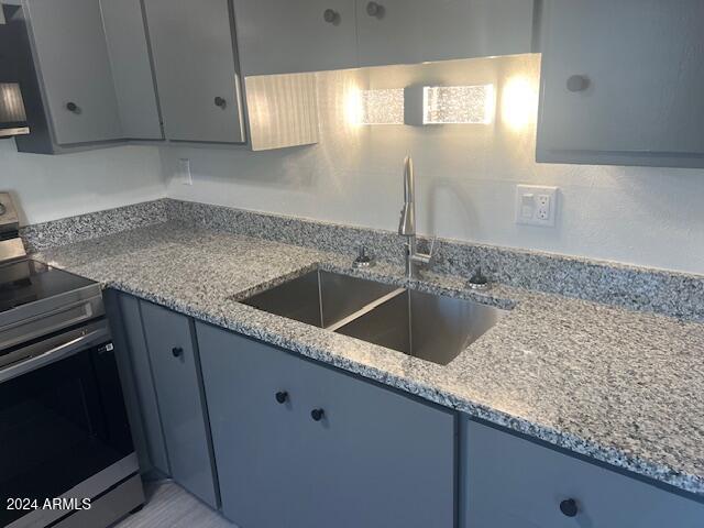 kitchen with light stone counters, sink, and stainless steel electric range