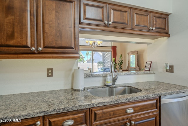 kitchen with stainless steel dishwasher, light stone countertops, a sink, and an inviting chandelier