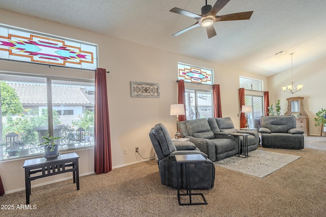 carpeted living room with baseboards, a wealth of natural light, vaulted ceiling, and ceiling fan with notable chandelier