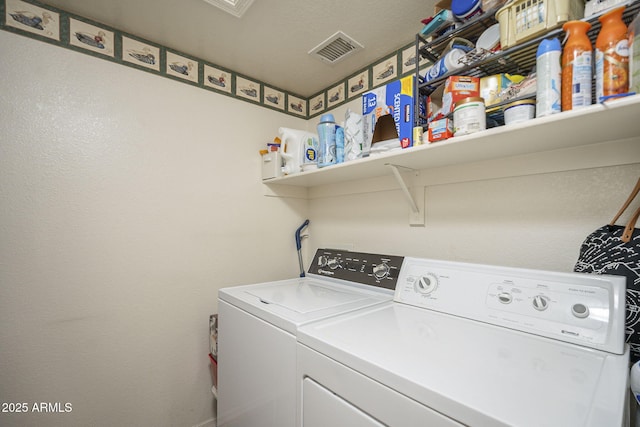 washroom with visible vents, washer and dryer, and laundry area