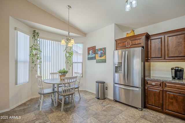 kitchen with an inviting chandelier, stone counters, stainless steel refrigerator with ice dispenser, stone finish floor, and lofted ceiling
