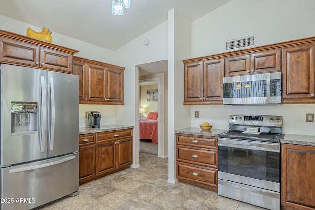 kitchen featuring light stone counters, stainless steel appliances, visible vents, baseboards, and high vaulted ceiling