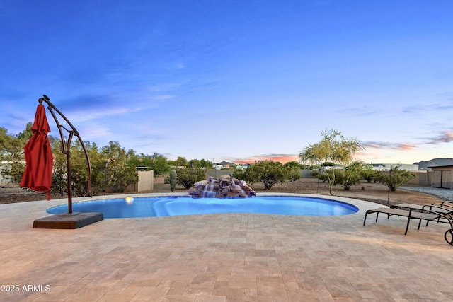 pool at dusk with an outdoor pool and a patio