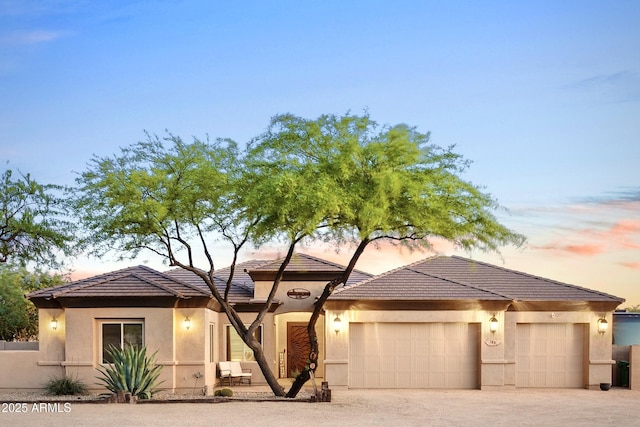 view of front of property with driveway, an attached garage, a tile roof, and stucco siding