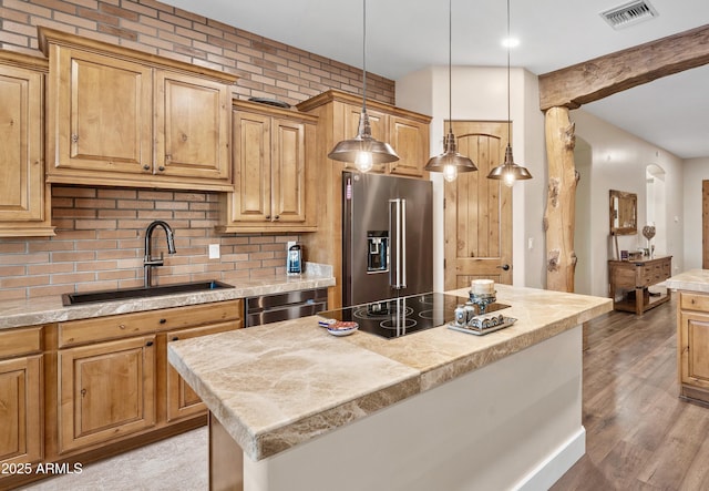 kitchen featuring stainless steel appliances, a sink, visible vents, light countertops, and decorative backsplash