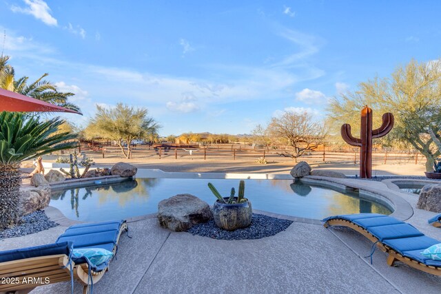 view of swimming pool with a rural view and a patio area