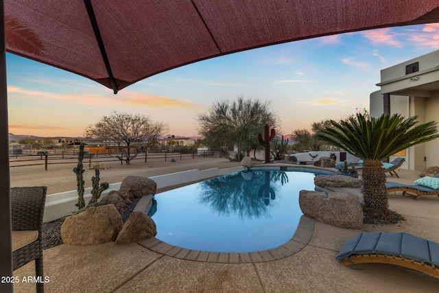 pool at dusk featuring a patio