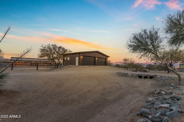 view of front facade featuring a garage, an outdoor structure, and a rural view