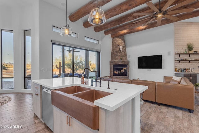 kitchen with sink, hanging light fixtures, stainless steel dishwasher, ceiling fan, and light hardwood / wood-style flooring