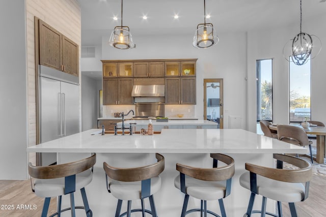 kitchen with a large island, extractor fan, tasteful backsplash, and hanging light fixtures