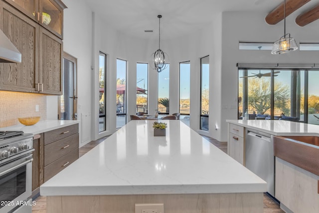 kitchen featuring decorative light fixtures, a chandelier, appliances with stainless steel finishes, a kitchen island, and backsplash