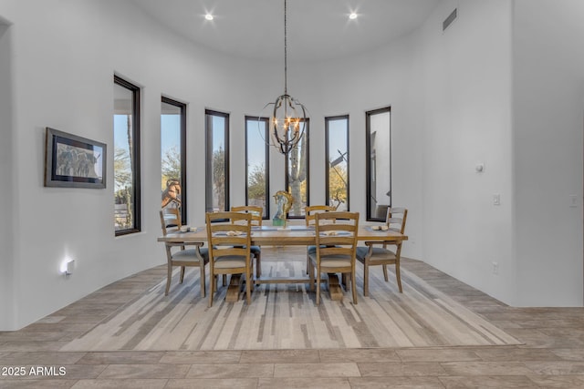 dining room with an inviting chandelier, a towering ceiling, and plenty of natural light