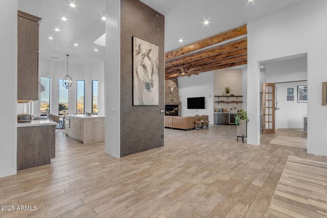 living room with a towering ceiling, an inviting chandelier, a fireplace, and light wood-type flooring