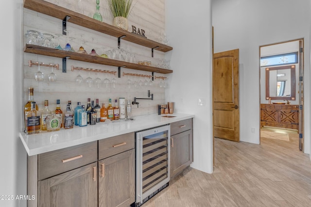 bar with wine cooler and light hardwood / wood-style flooring