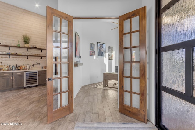 entryway featuring indoor bar, beverage cooler, light wood-type flooring, and french doors