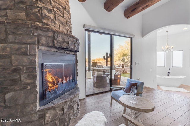 living room with an inviting chandelier, beam ceiling, and a large fireplace