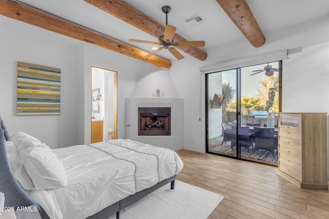 bedroom with ensuite bathroom, a fireplace, beamed ceiling, access to outside, and light wood-type flooring