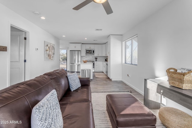 living room featuring ceiling fan, a healthy amount of sunlight, and light wood-type flooring