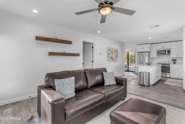 living room featuring ceiling fan and light hardwood / wood-style flooring