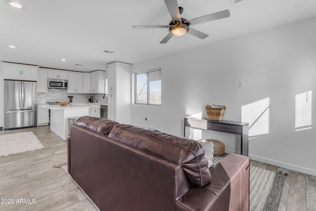 living room with ceiling fan and light hardwood / wood-style floors