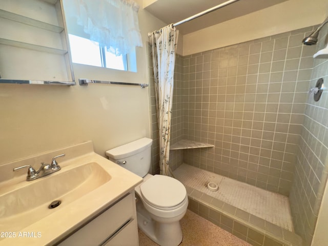 bathroom with toilet, a tile shower, and vanity