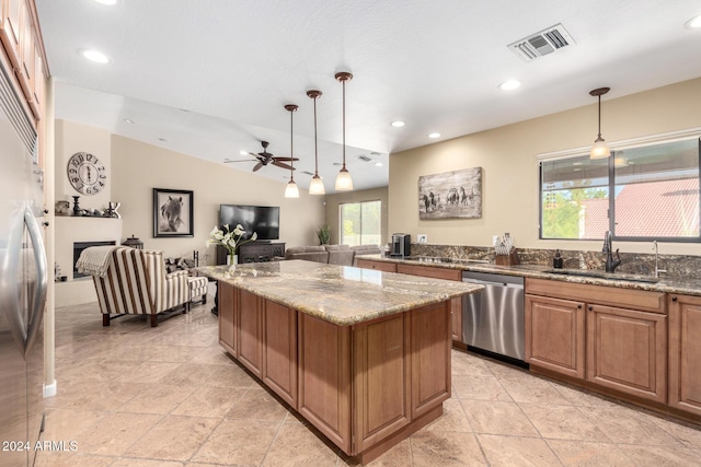 kitchen featuring stone counters, pendant lighting, stainless steel appliances, and sink