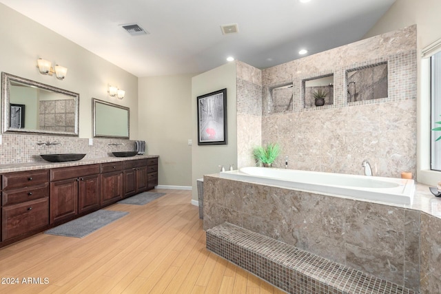 bathroom featuring tiled tub, hardwood / wood-style floors, and vanity