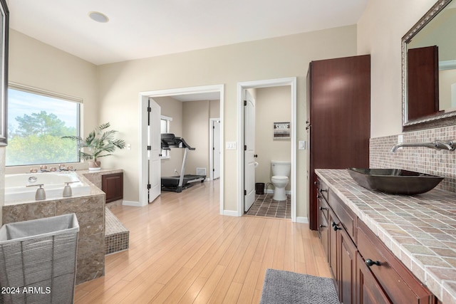 bathroom featuring backsplash, vanity, hardwood / wood-style flooring, toilet, and a bathing tub