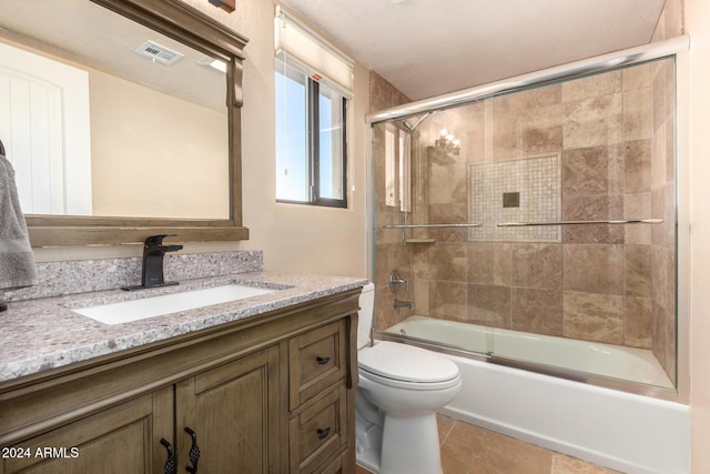 full bathroom with combined bath / shower with glass door, vanity, tile patterned floors, and toilet