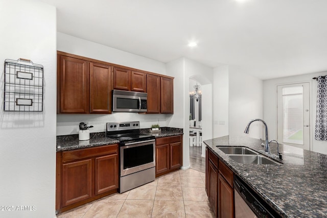 2986 E Country Shadows St, Gilbert, AZ 85298 - kitchen with appliances with stainless steel finishes, a sink, dark stone countertops, a chandelier, and arched walkways