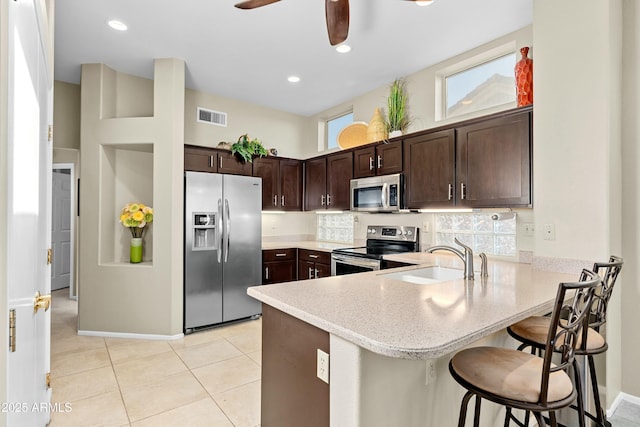 kitchen featuring a kitchen breakfast bar, stainless steel appliances, kitchen peninsula, and sink