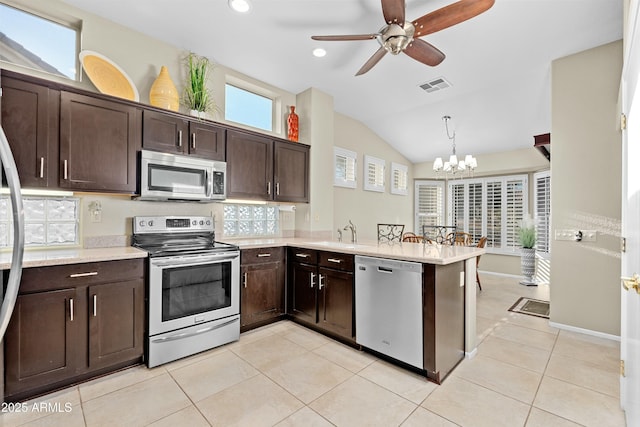 kitchen featuring kitchen peninsula, stainless steel appliances, hanging light fixtures, ceiling fan with notable chandelier, and dark brown cabinetry