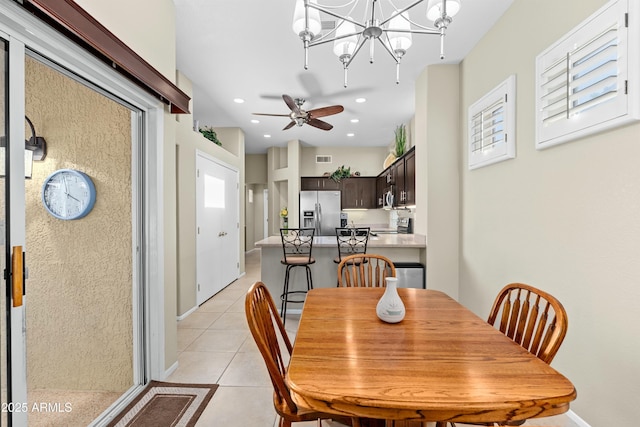 tiled dining area featuring ceiling fan with notable chandelier